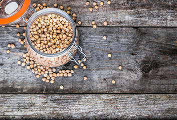 Raw chickpeas in rustic jar on wooden table, healthy vegan cooking ingredients