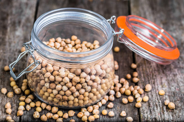 Raw chickpeas in rustic jar on wooden table, healthy vegan cooking ingredients