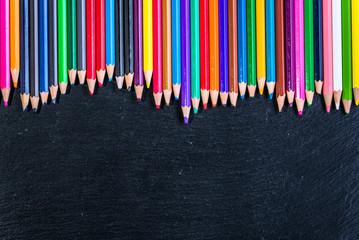 Colorful pencils frame background on black, copy space