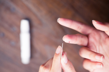 Close up of asian woman hands using lancet on finger to check blood sugar level by glucose meter, Healthcare medical and check up, diabetes, glycemia, and people concept