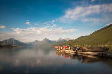 Fototapeta premium Boats on an empty Lake McDonald with mountains in the back