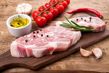 Raw meat. Pork steak with herbs  spices and vegetables on cutting board