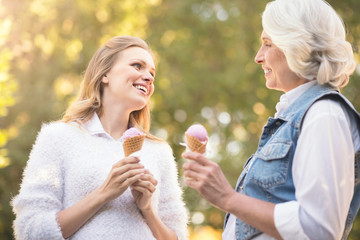 Fototapeta premium Elderly woman tasting ice cream with mature daughter outdoors