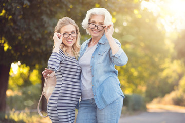 Retired woman having fun with young pregnant daughter outdoors