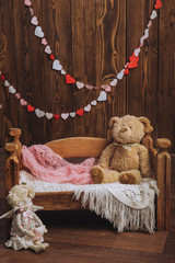 Toy bear on a wooden crib  and a vintage rag doll angel. Studio photography close-up, the...