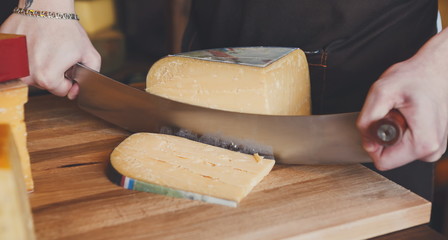 Cutting hard cheese in grocery shop