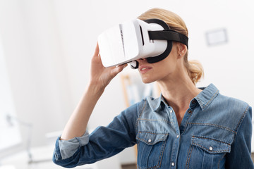 Charming woman using visual reality headset indoors