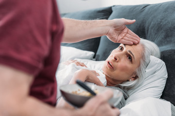 selective focus of man taking care of sick wife in bed at home