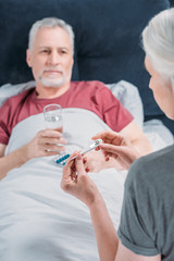 woman looking at thermometer while taking care of sick husband