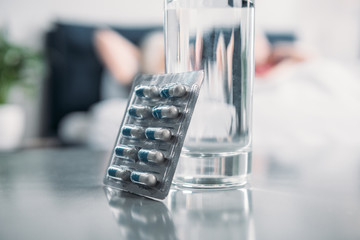 selective focus of glass of water and medicines on table in room