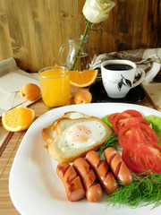 Fried eggs with sausages and tomatoes on a white plate surrounded by fruit