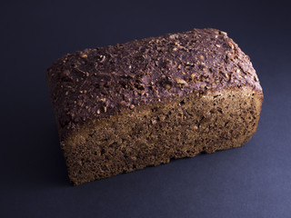 Whole Danish rye bread made from sour dough with whole grain flour and seeds,  isolated on black background