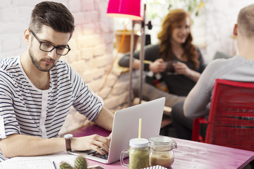 Student writing on computer in cafe