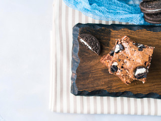 Cream cheese chocolate layer brownies with cookies on wooden serving board