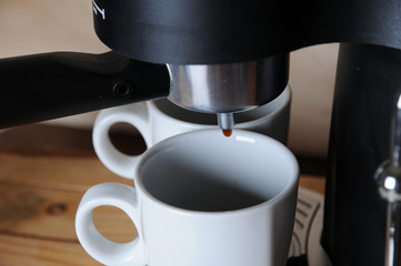 Coffee from the coffee machine is poured into white cups, close-up