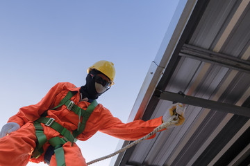 Working at height equipment . Builder Worker in safety protective equipment on roof construction site .