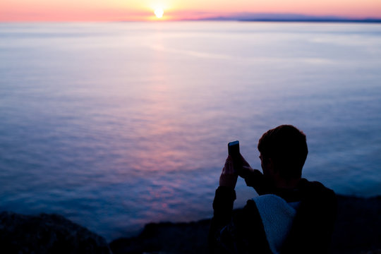 man photographer taking photos of sunset at the sea