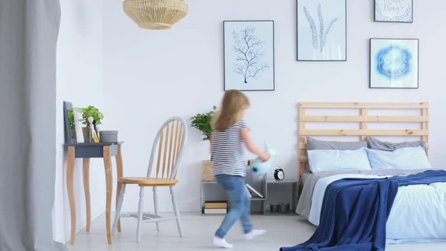 Girl playing in her parents stylish blue bedroom
