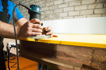 Professional carpenter processes the plastic edges of the countertop. The concept of furniture production