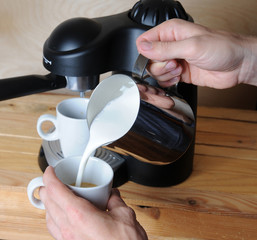 Barista man is making cappuccino. Pours milk closeup