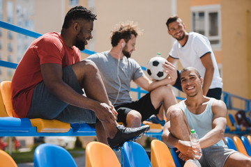 multicultural soccer team resting on stadium together before game