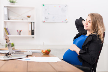Pregnant businesswoman eating salad at office