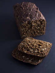 Danish rye bread made from sour dough with whole grain flour and seeds. Sliced and isolated on black background