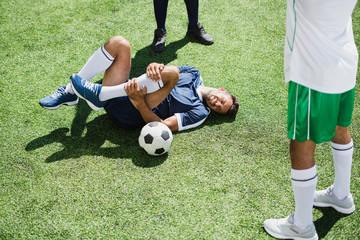 injured soccer player lying on football field during match