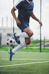 Fototapeta premium cropped shot of athletic soccer player training with ball on soccer pitch