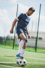 athletic soccer player training with ball on soccer pitch © LIGHTFIELD STUDIOS