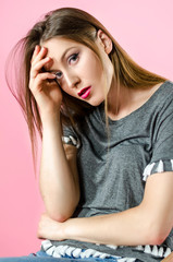 Portrait of young attractive woman with long straight blonde hair, pink background