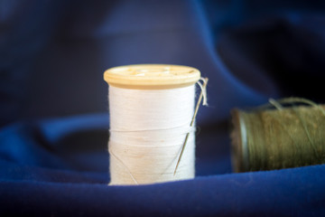 thread with needle on blue fabric