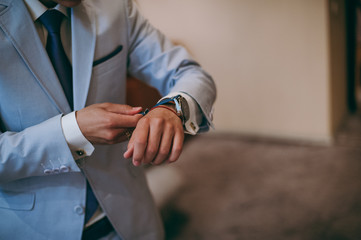 Obraz premium A man putting on watch. The bridegroom at the wedding with the clock
