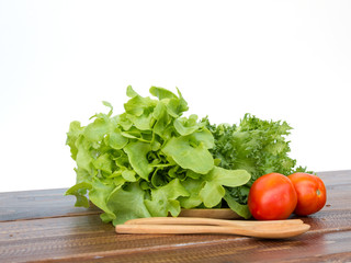 salad set are tomato, Frilly Iceberg and green oak placing on wooden tray with spoon and fork on white background