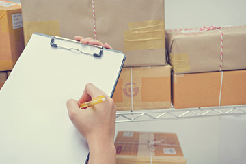 Business woman is showing a clipboard in hand and checking boxes in a warehouse