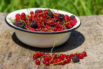 Fresh colorful berries in bowl on rustic wooden table