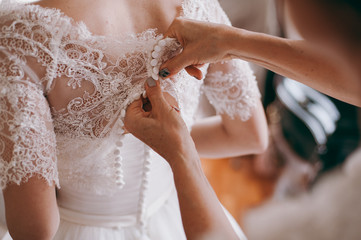 Fashionable bridesmaids dresses helped wear bow on back of wedding dress bride. Morning wedding day.
