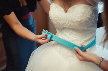 Obraz na płótnie Canvas Fashionable bridesmaids dresses helped wear bow on back of wedding dress bride. Morning wedding day.