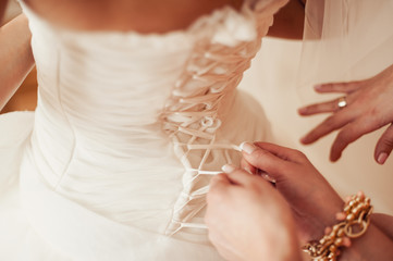 Fashionable bridesmaids dresses helped wear bow on back of wedding dress bride. Morning wedding day.