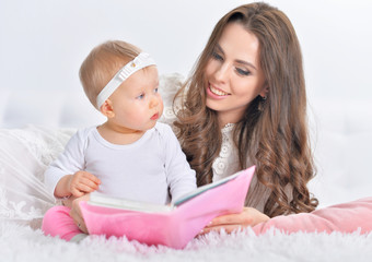 Beautiful young mother with daughter reading book