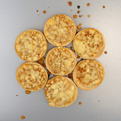 A group of cooked mini cheese pizza bagels on a baking pan.