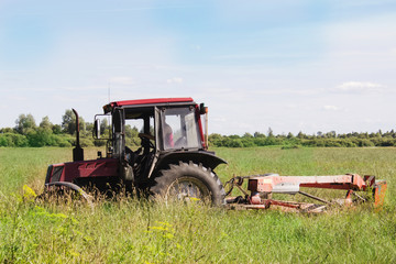 Old small tractor mows the grass