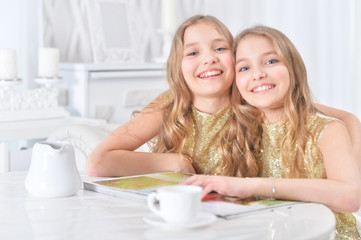 cute twin sisters with modern magazine