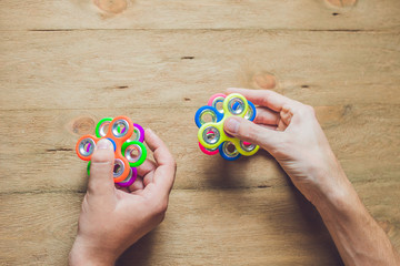 A man hand holding hand spinner or fidget spinner over wooden background