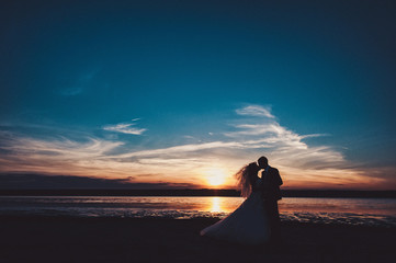 Fototapeta na wymiar Wedding couple on a walk bride and groom sea field sunset architecture grass sand