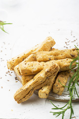 Bread sticks from puff pastry with flax and sesame seeds on a light background with rosemary. Top View.