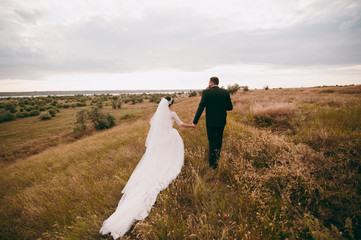 Wedding couple on a walk bride and groom sea field sunset architecture grass sand