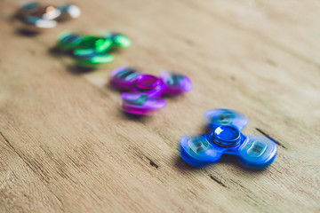Colored fidget spinners stress relieving toy on wooden background