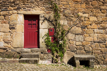 Detail of a stone house with a red door in the historic village of Idanha a Velha in Portugal; Concept for travel in Portugal