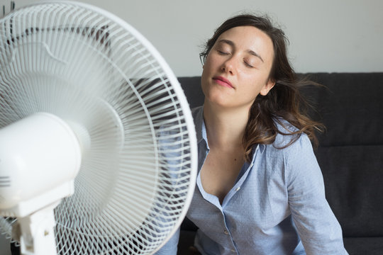 Young Woman Refreshing In Front Of Cooling Fan